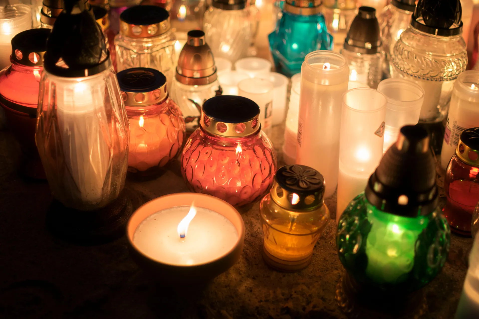 Colorful votive candles creating a warm, spiritual ambiance at an outdoor memorial.