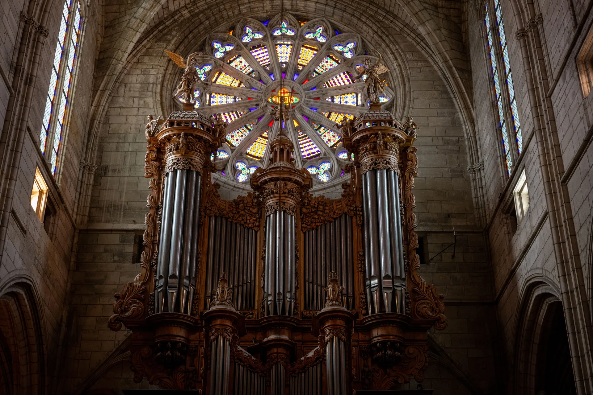Majestic pipe organ inside a historic French cathedral with intricate stained glass.