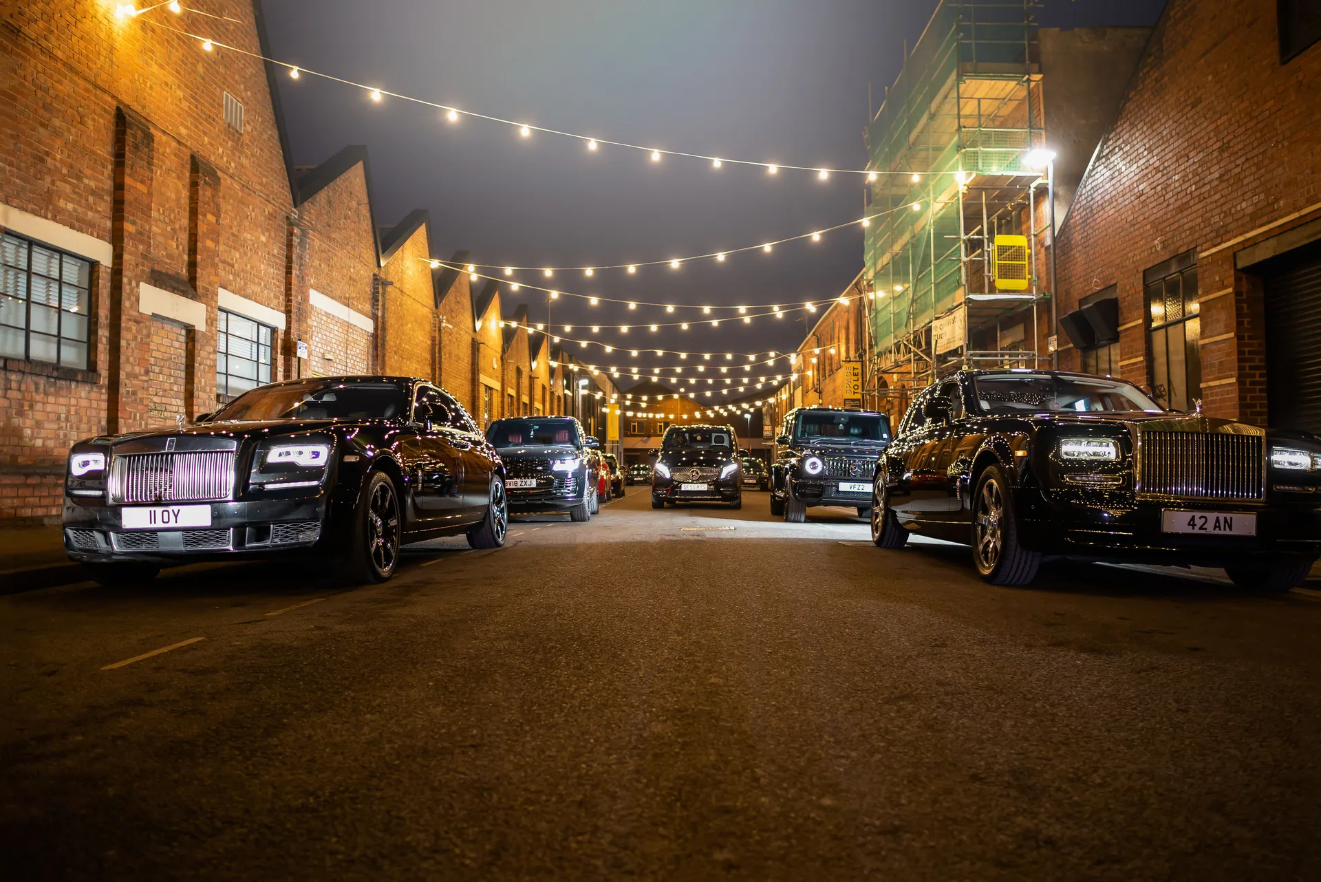 Elegant display of luxury cars under streetlights during a nighttime urban setting.
