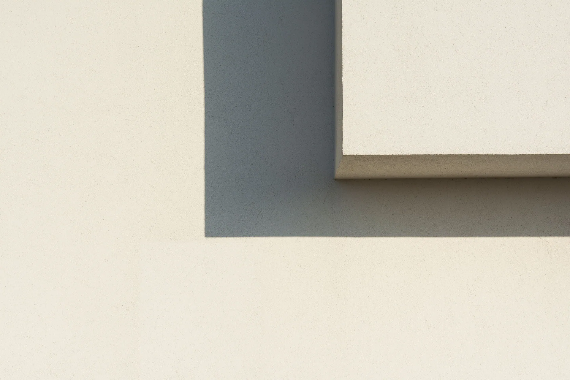 Abstract minimalist image showcasing geometric shadows on a white wall.