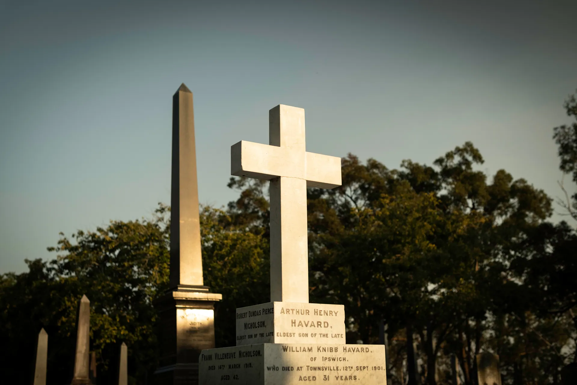 Sunset casts an eerie glow over historic obelisks and crosses in Toowong Cemetery, Brisbane.