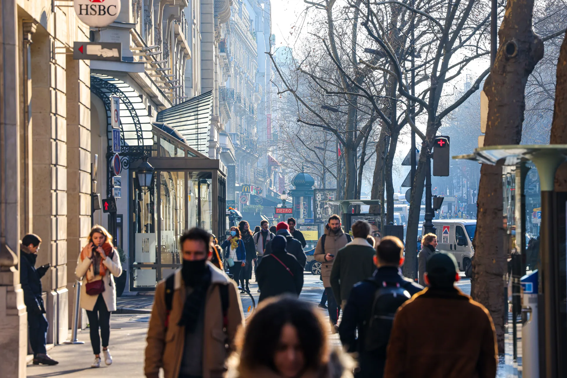 Crowded urban street with people walking on a sunny day.