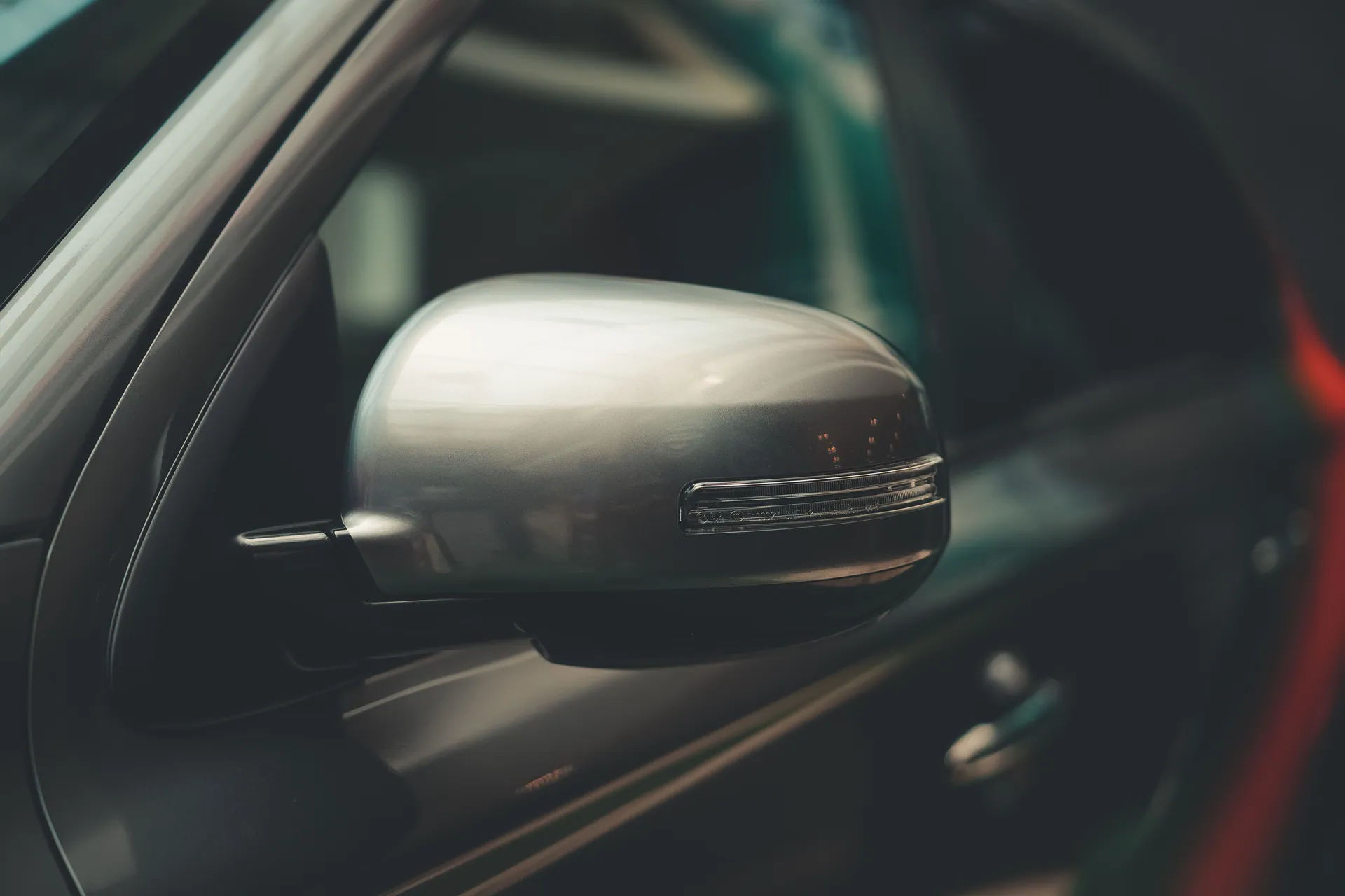 A detailed close-up of a car's chrome side mirror, showcasing modern design.