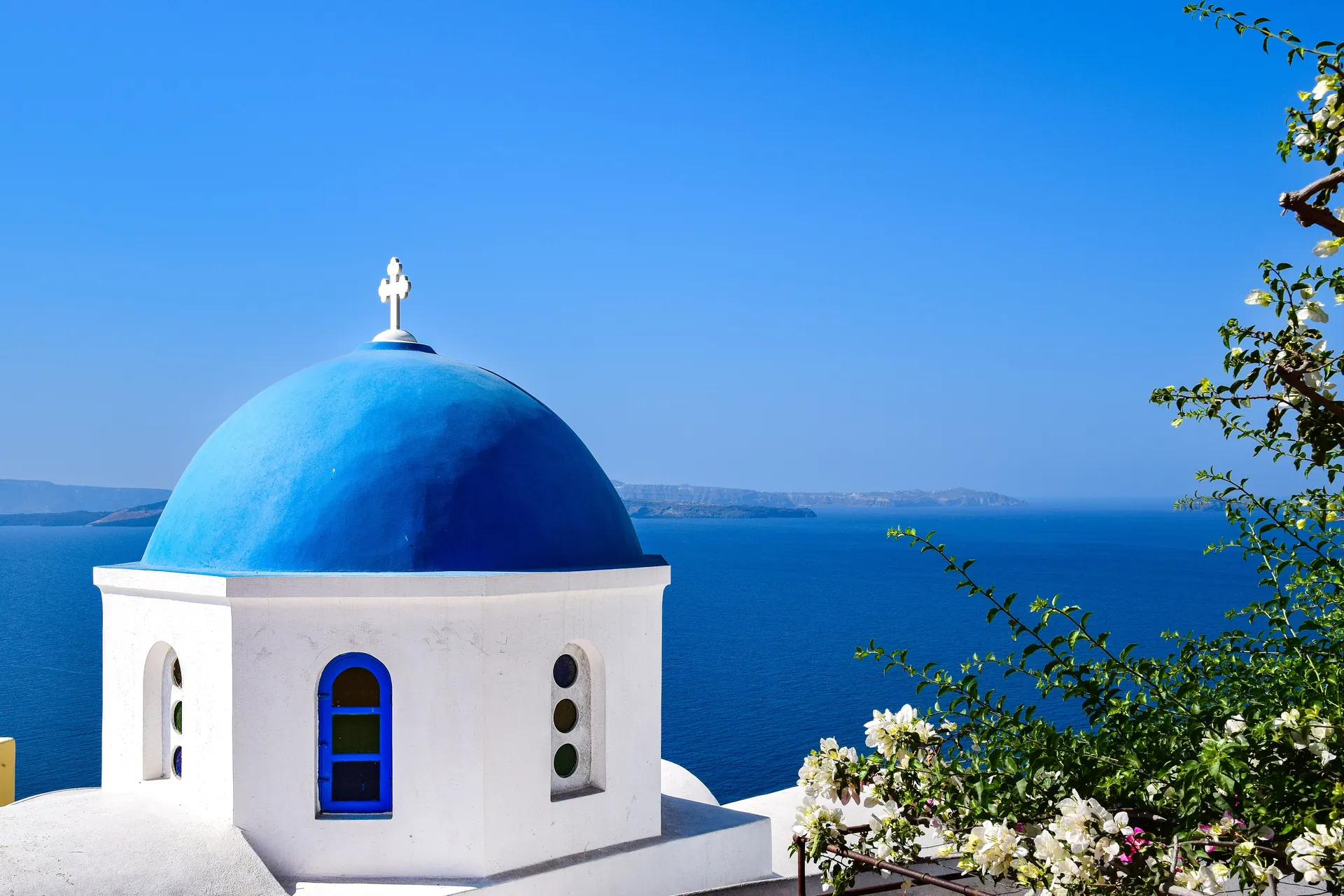 Stunning view of a blue domed church overlooking the Aegean Sea in Santorini, Greece.