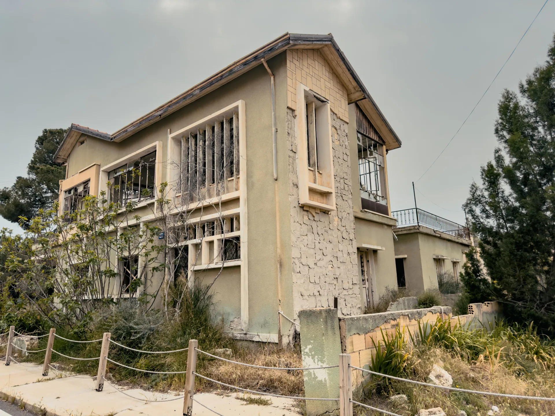 A decaying building in Cyprus surrounded by wild plants, depicting urban decay.