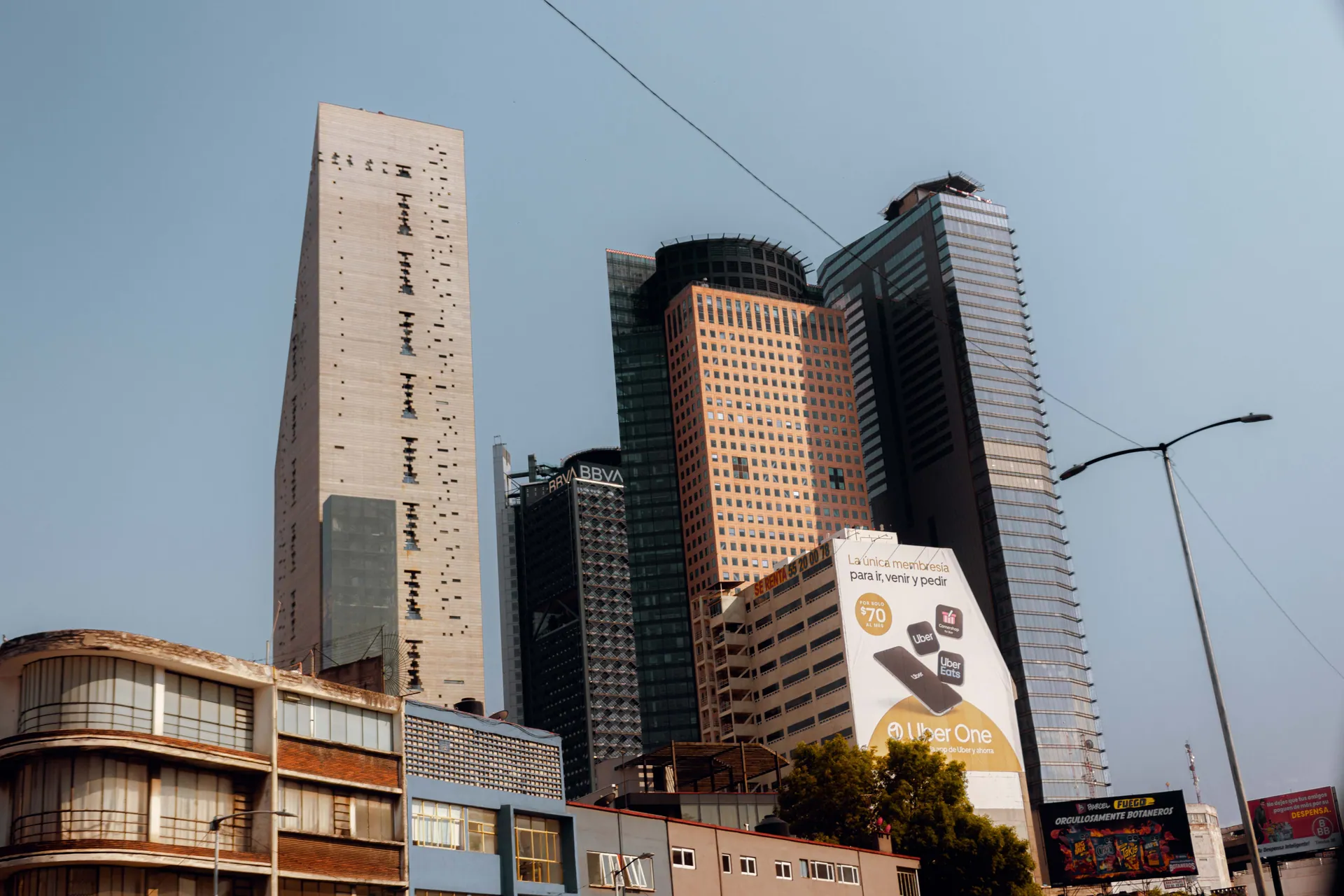 Low angle view of diverse skyscrapers in a bustling cityscape under clear skies.