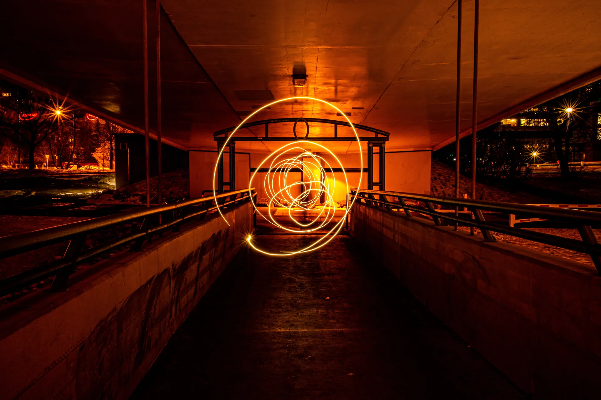 Dramatic light spirals in a dark urban tunnel, showcasing long exposure photography at night.