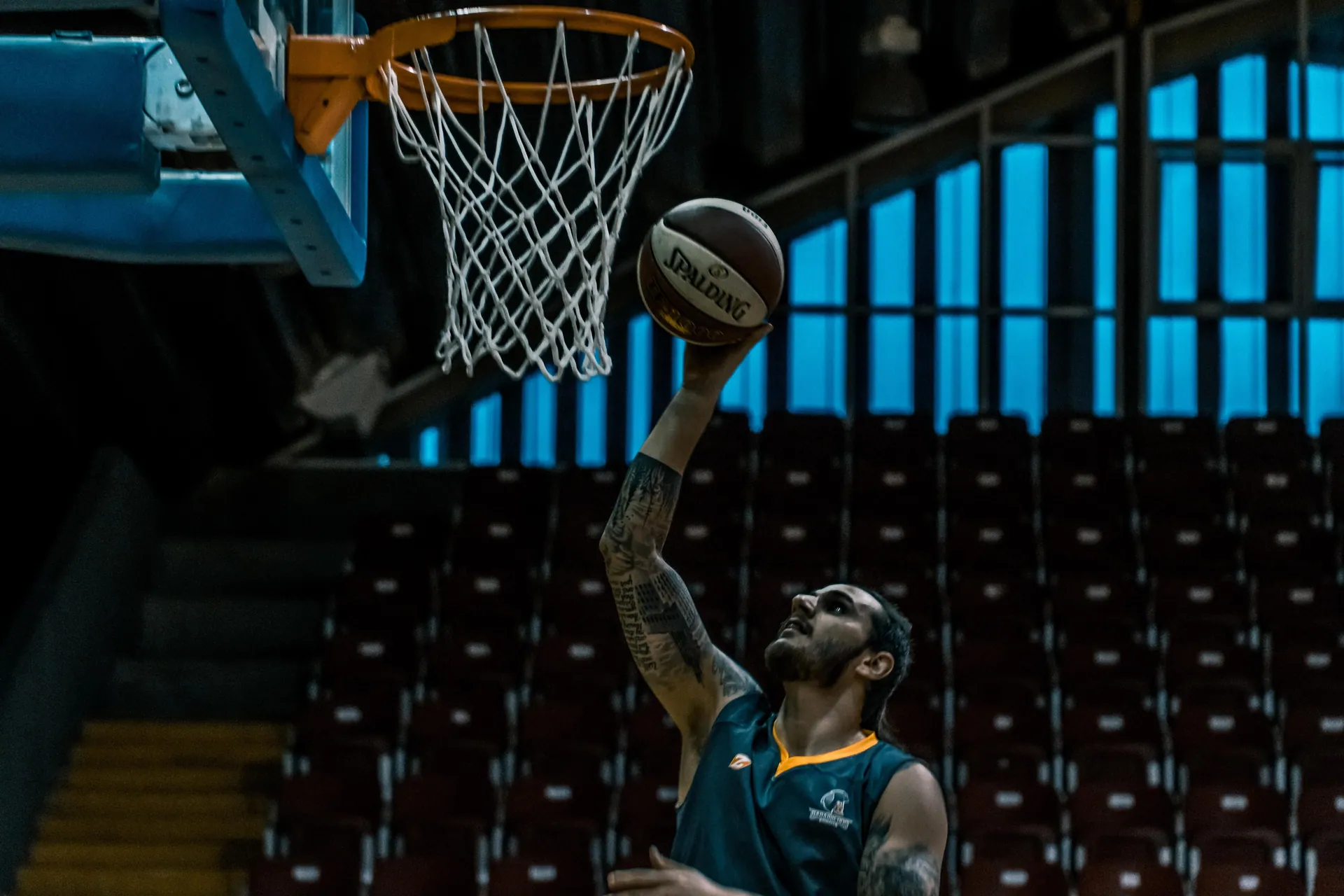 A focused basketball player scores a point in a dimly lit indoor court, showcasing athletic talent.