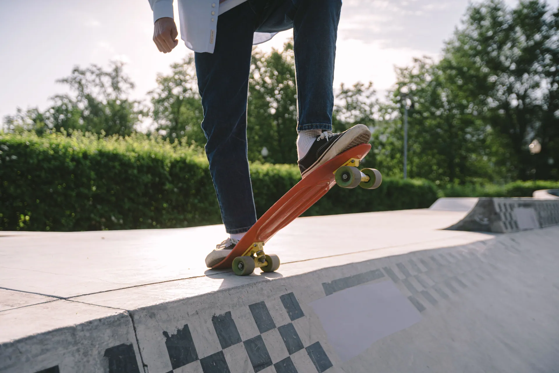 Close-up of a skateboarder performing a trick in a sunlit skate park.