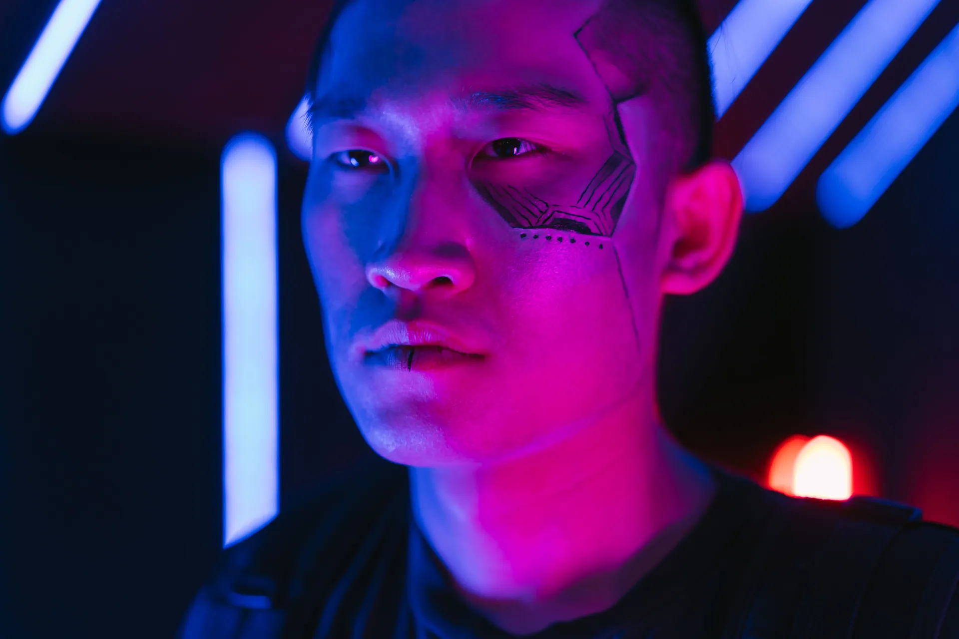 Cyberpunk-themed portrait of a man in neon lighting, showcasing a futuristic face tattoo.