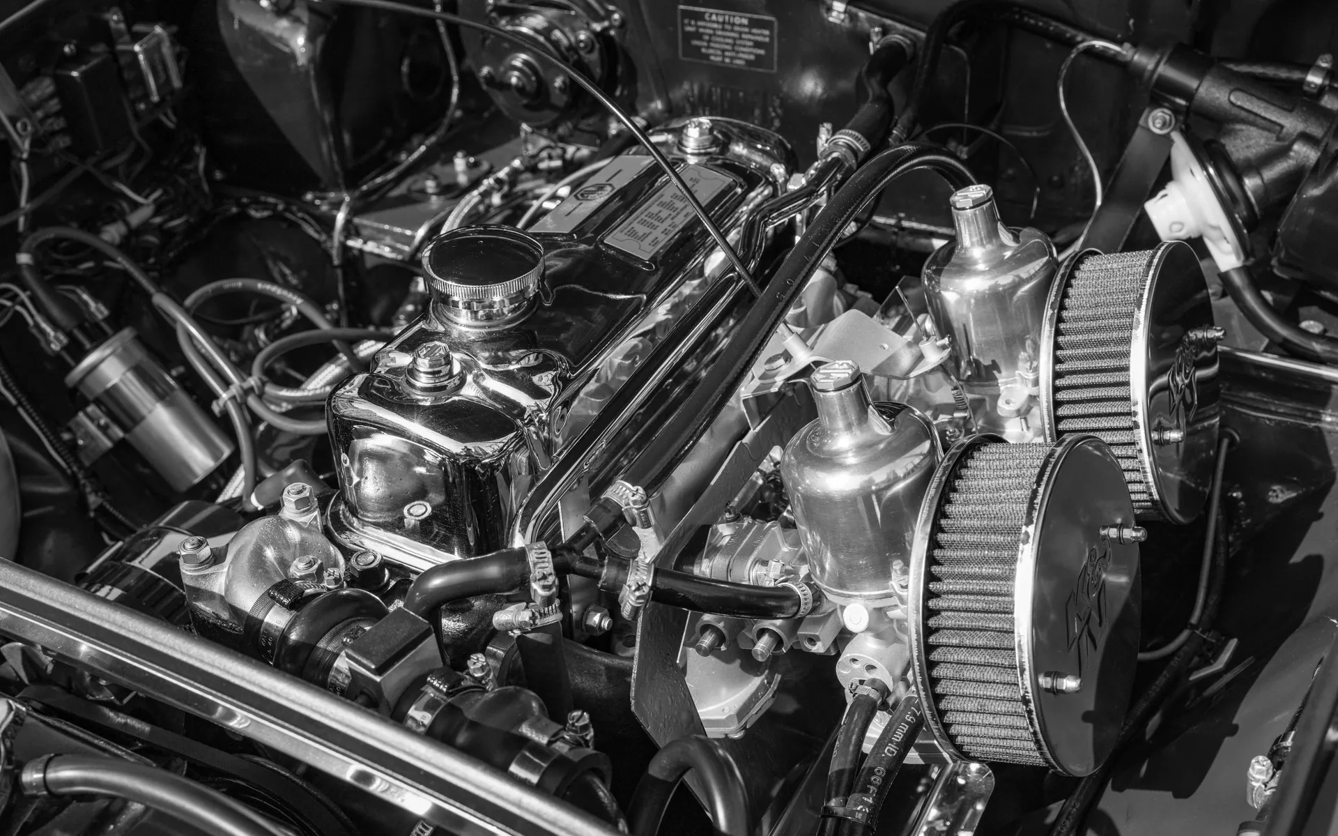 Detailed close-up of a classic car engine, highlighting chrome and mechanical components.