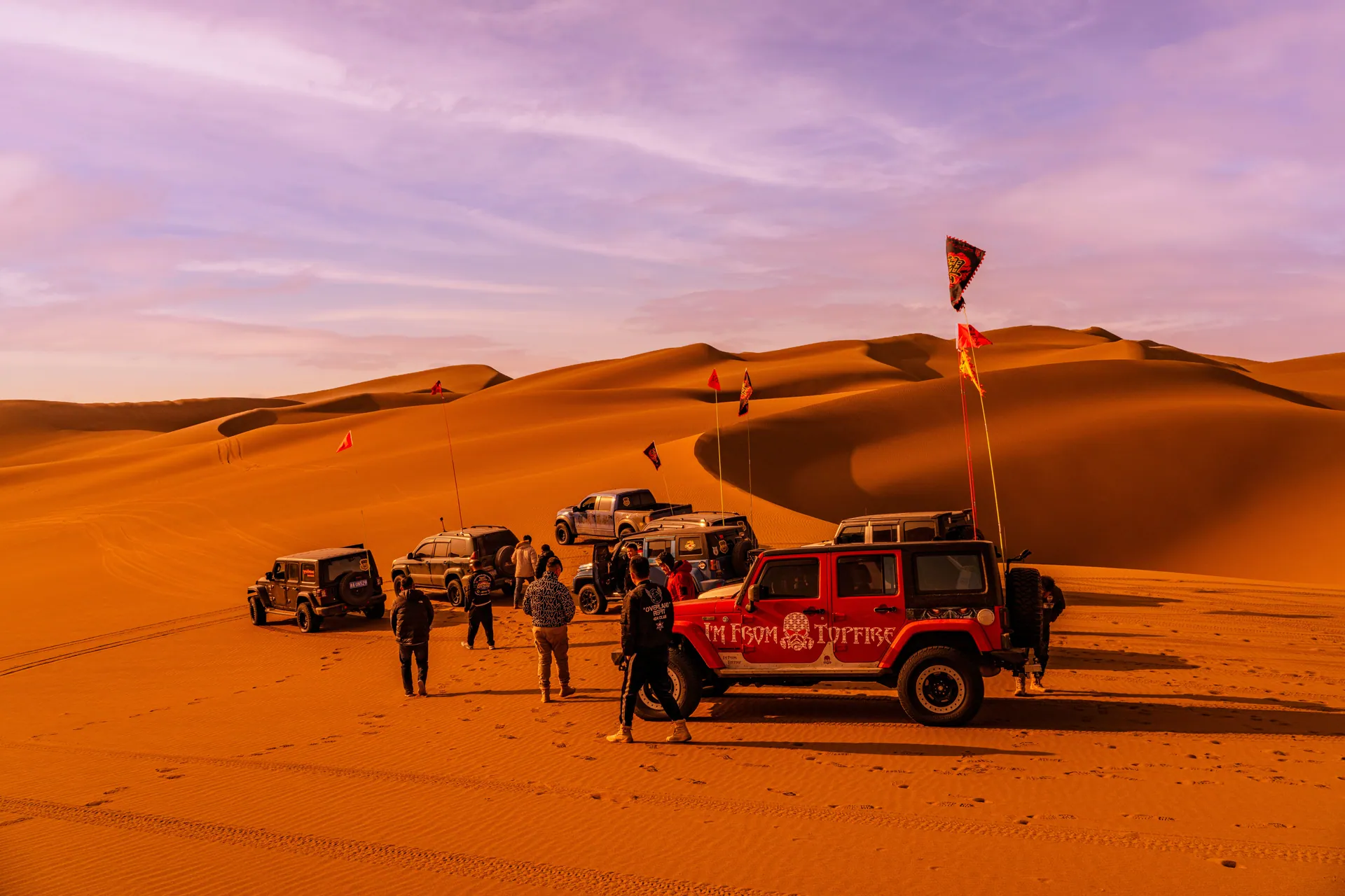 Group of SUVs and people enjoying an off-road desert adventure.