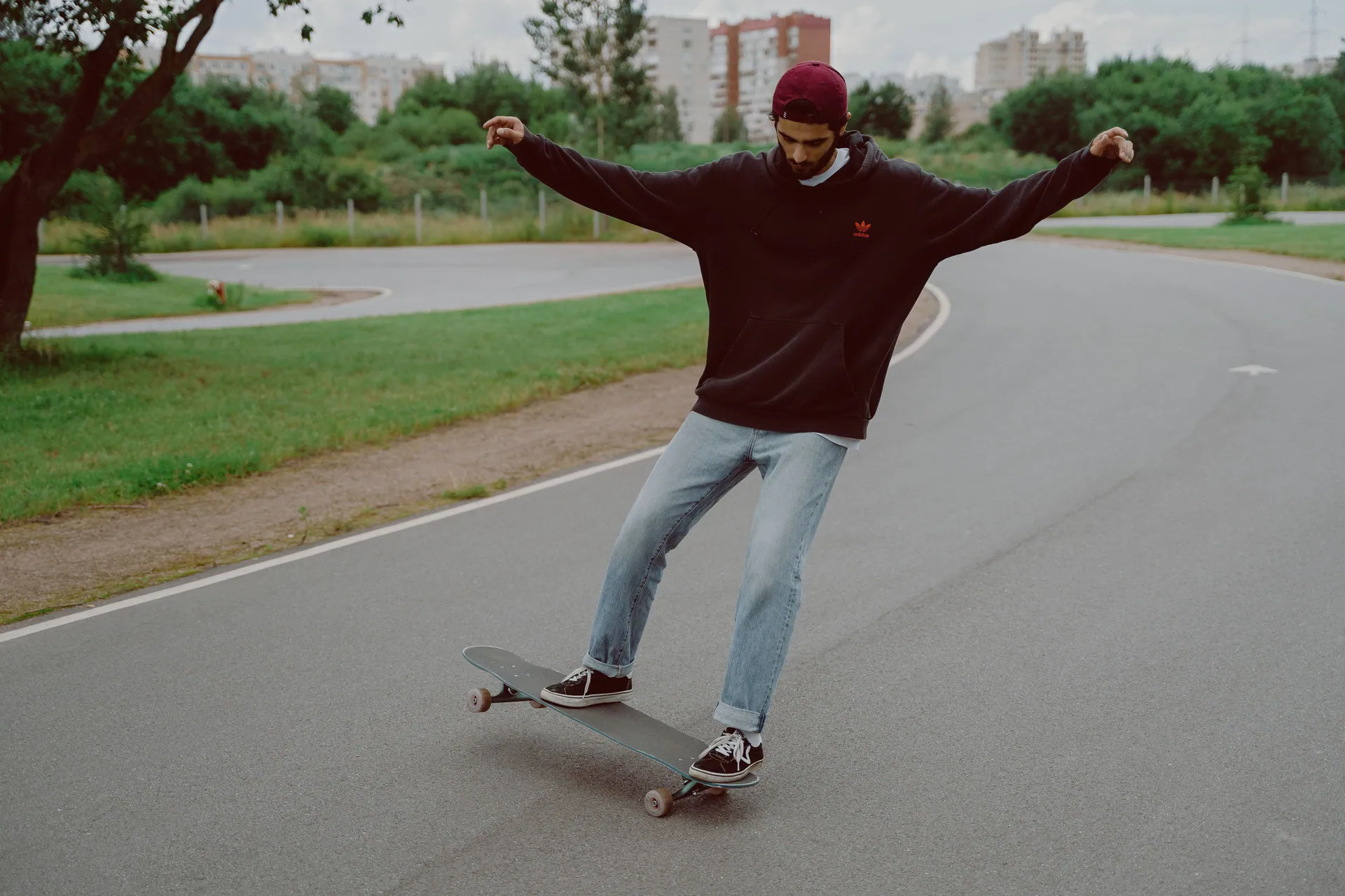 A young man skateboarding on a curved path in a park, showcasing skill and leisure.