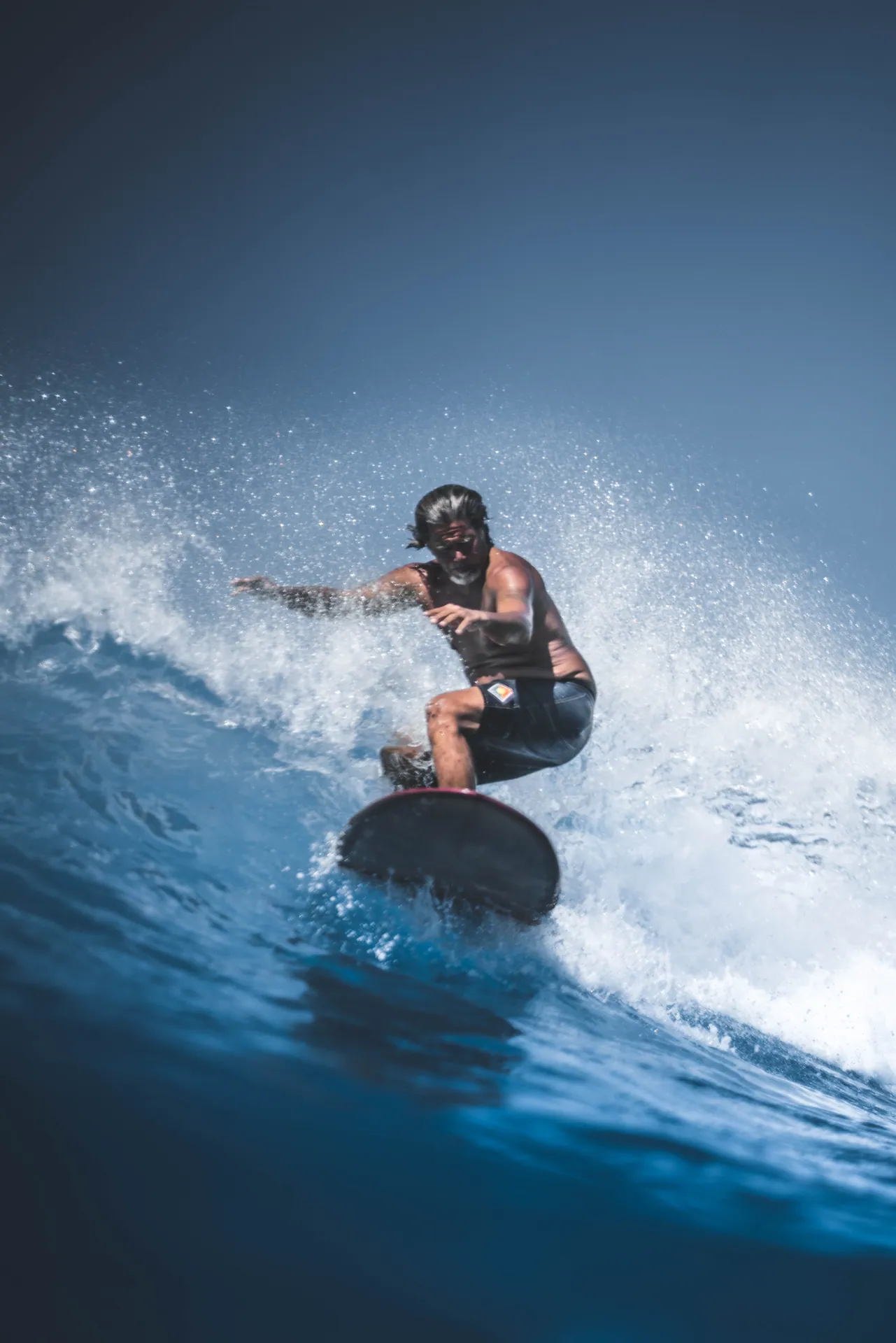 Catch the thrill of surfing with a man riding the waves in vibrant blue waters. Perfect for sports enthusiasts.