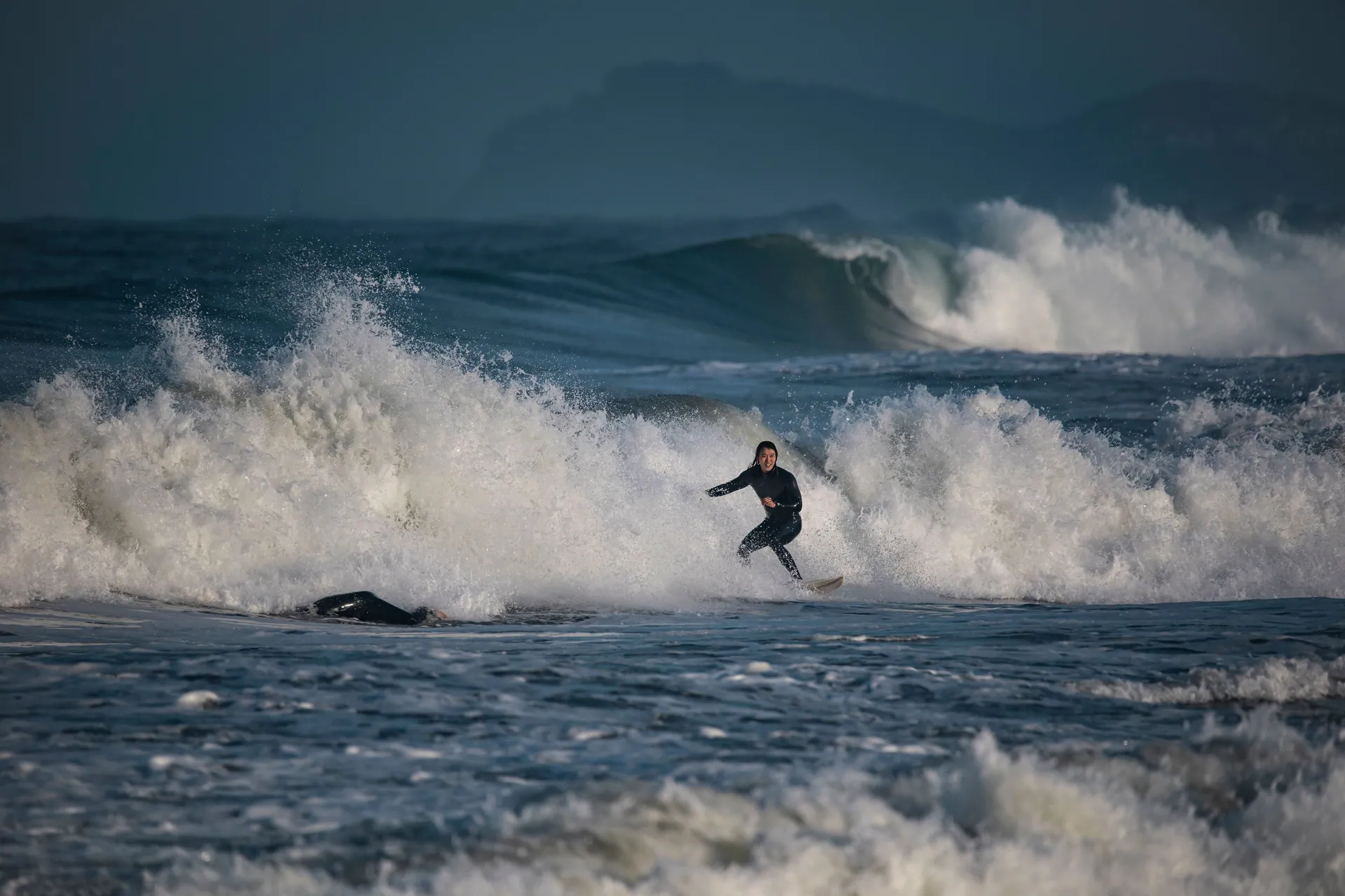 A surfer skillfully rides waves along the coastline of Yangyang, South Korea.