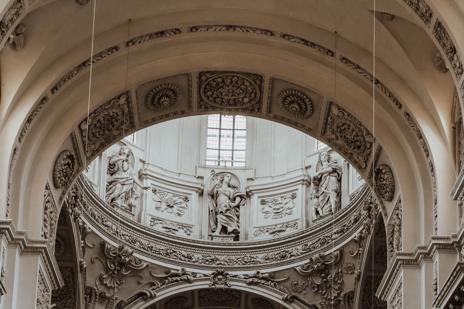 A detailed view of ornate Baroque arches and sculptures in a cathedral ceiling, showcasing classic European architecture.