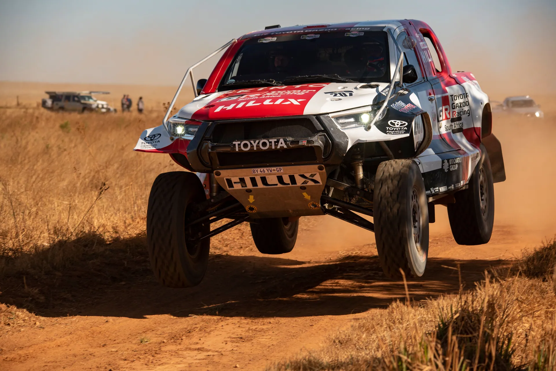 High-speed off-road racing truck jumping over dirt track during a rally competition.