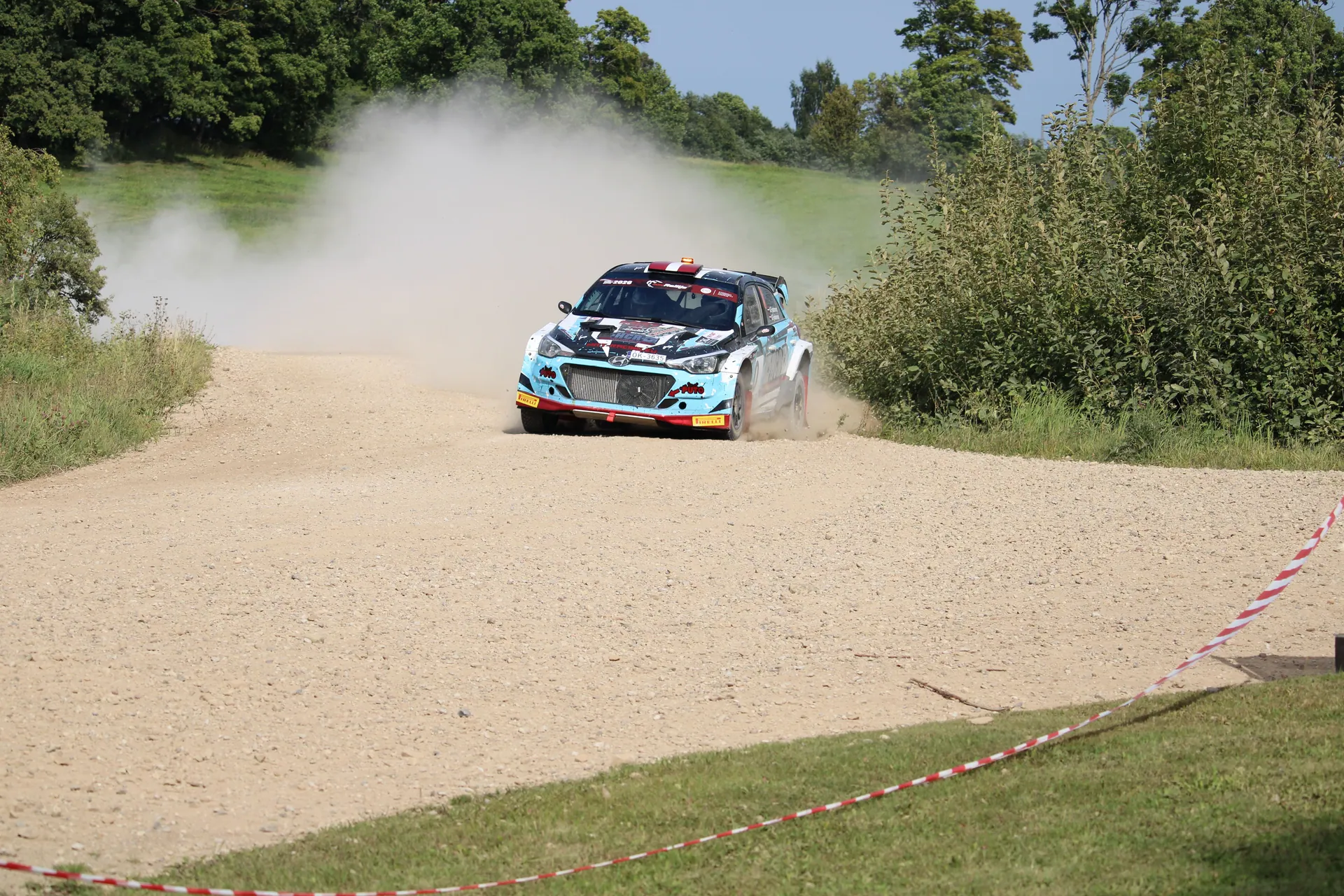 Exciting rally car race on a gravel road in Cesvaine, Latvia, capturing speed and dust.