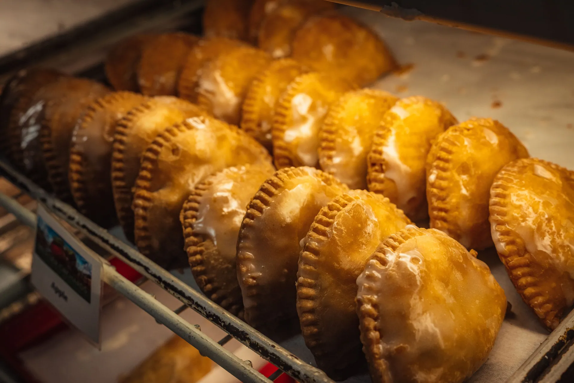 Homemade golden hand pies arranged on a bakery display shelf, inviting and fresh.
