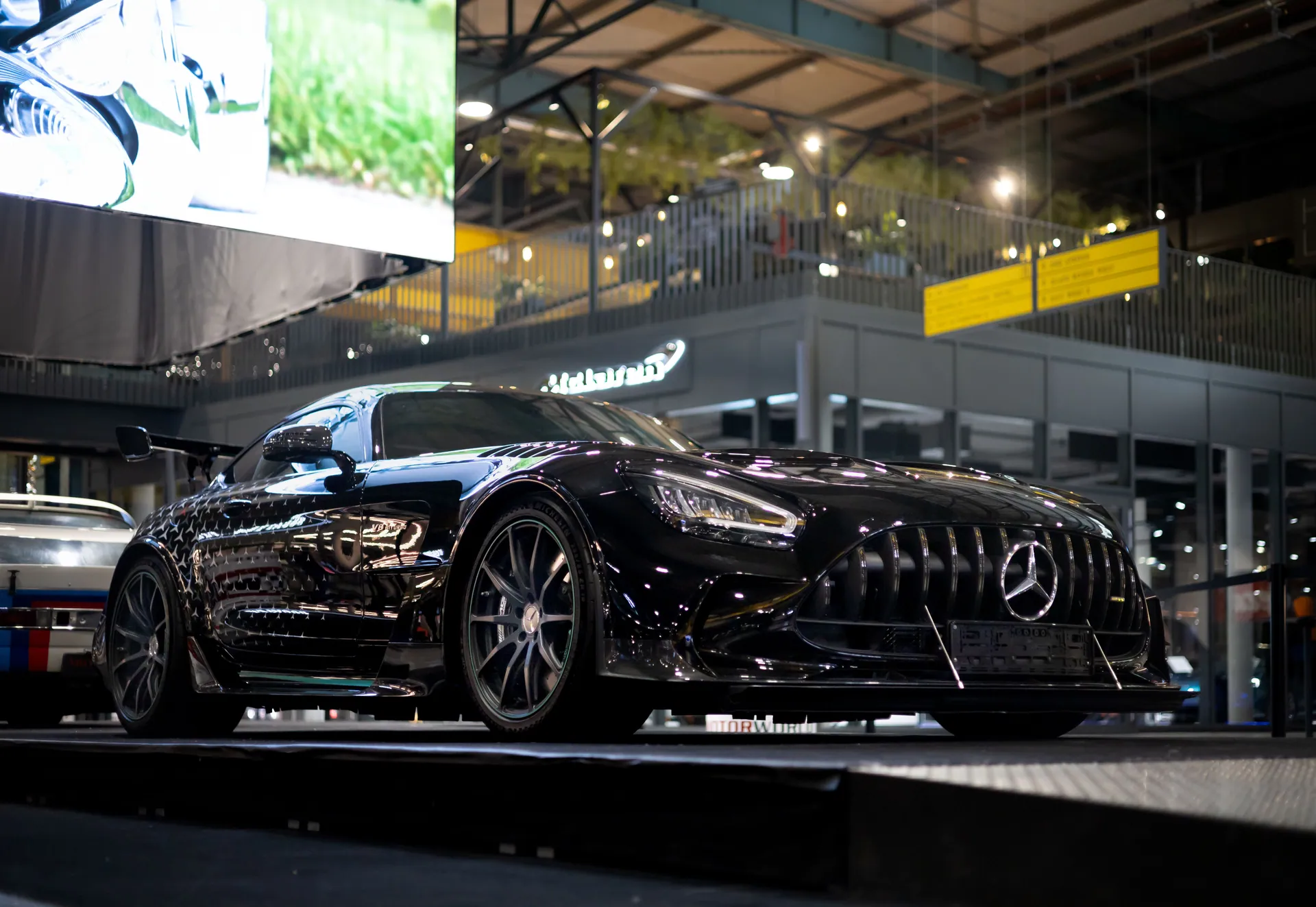 Sleek black luxury sports car showcased at a Munich automotive exhibition, highlighting elegance.