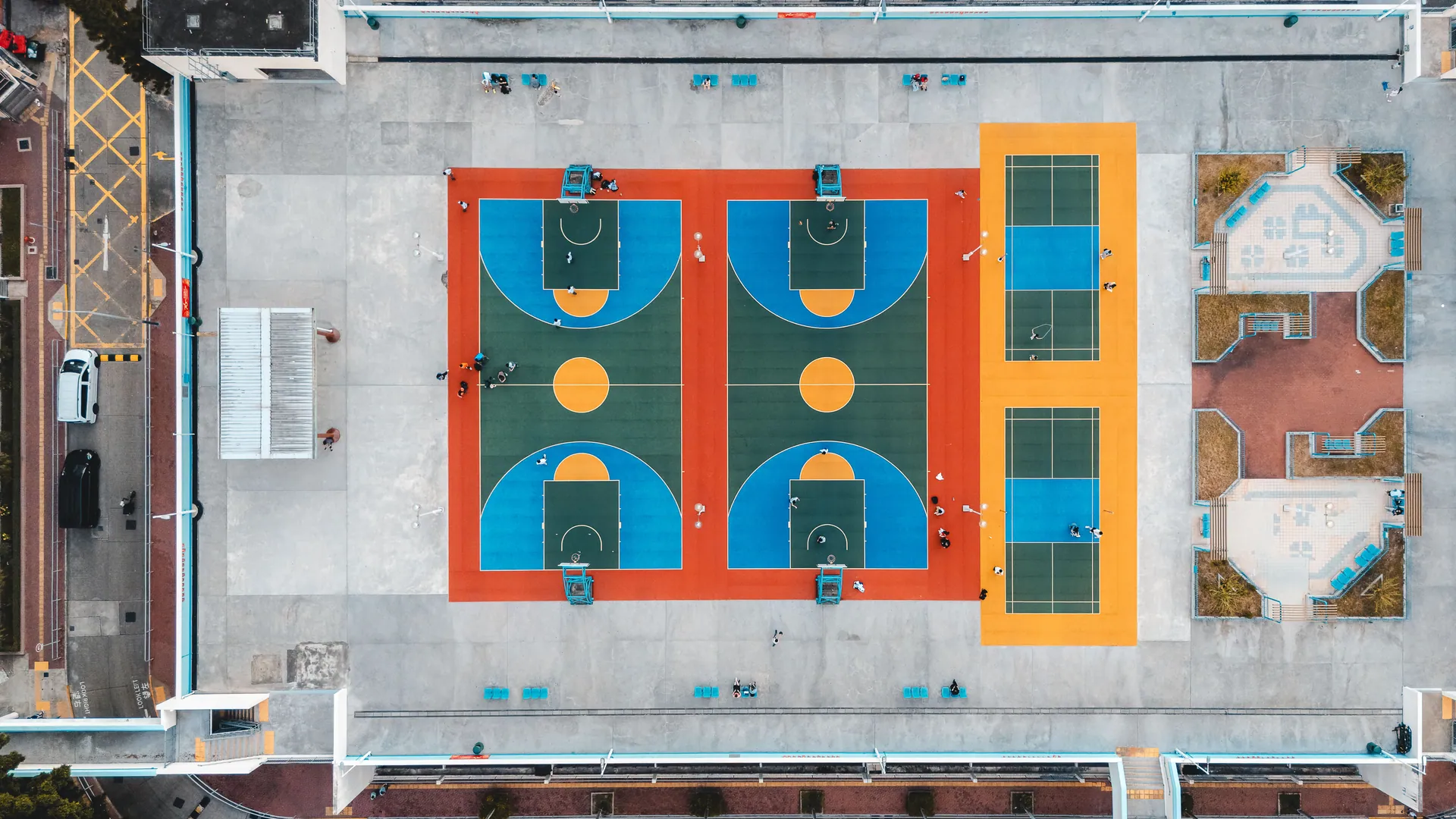Aerial shot of vibrant basketball and tennis courts in Kowloon, Hong Kong, showcasing urban recreation.