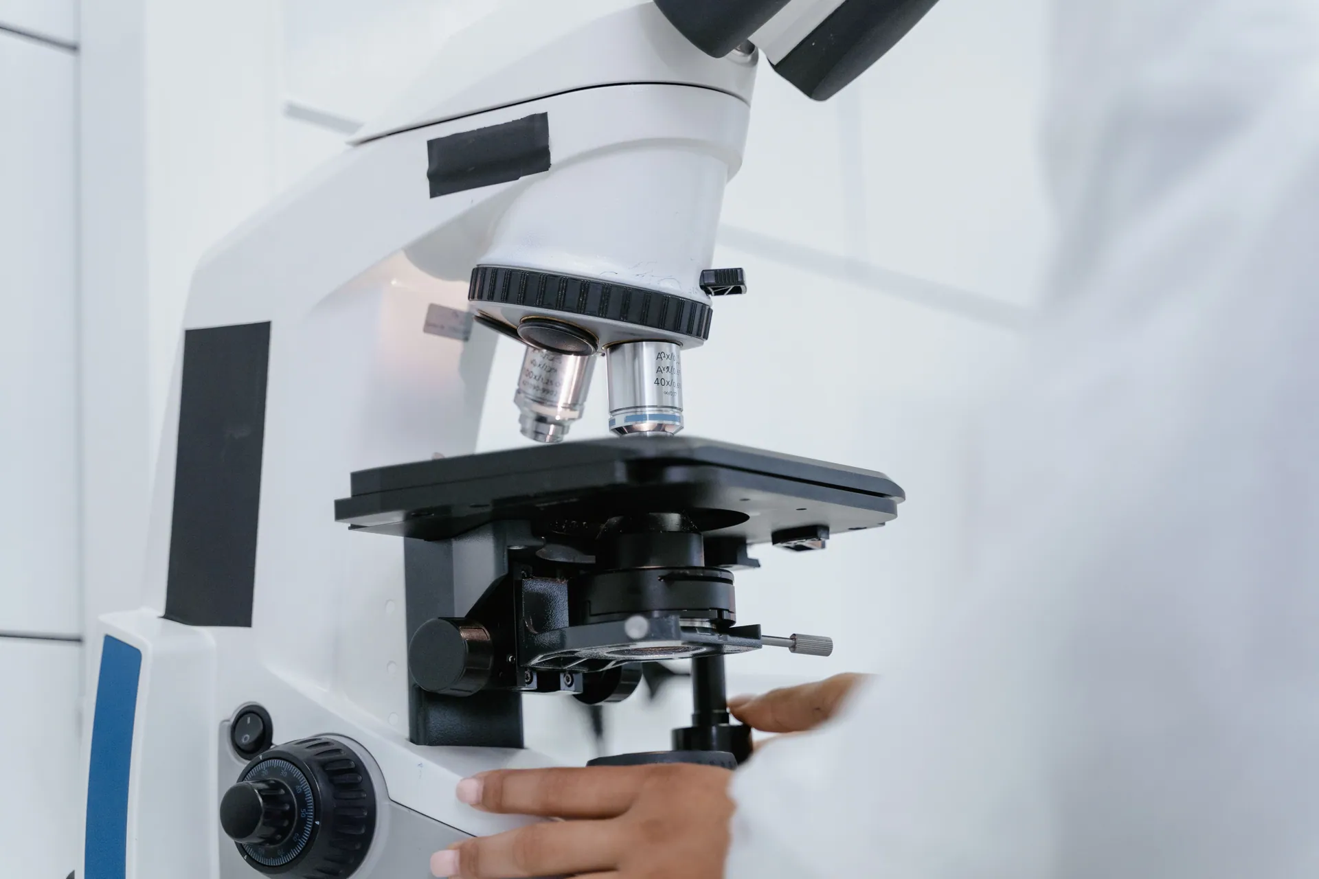 Detailed view of a scientist operating a microscope in a laboratory setting.