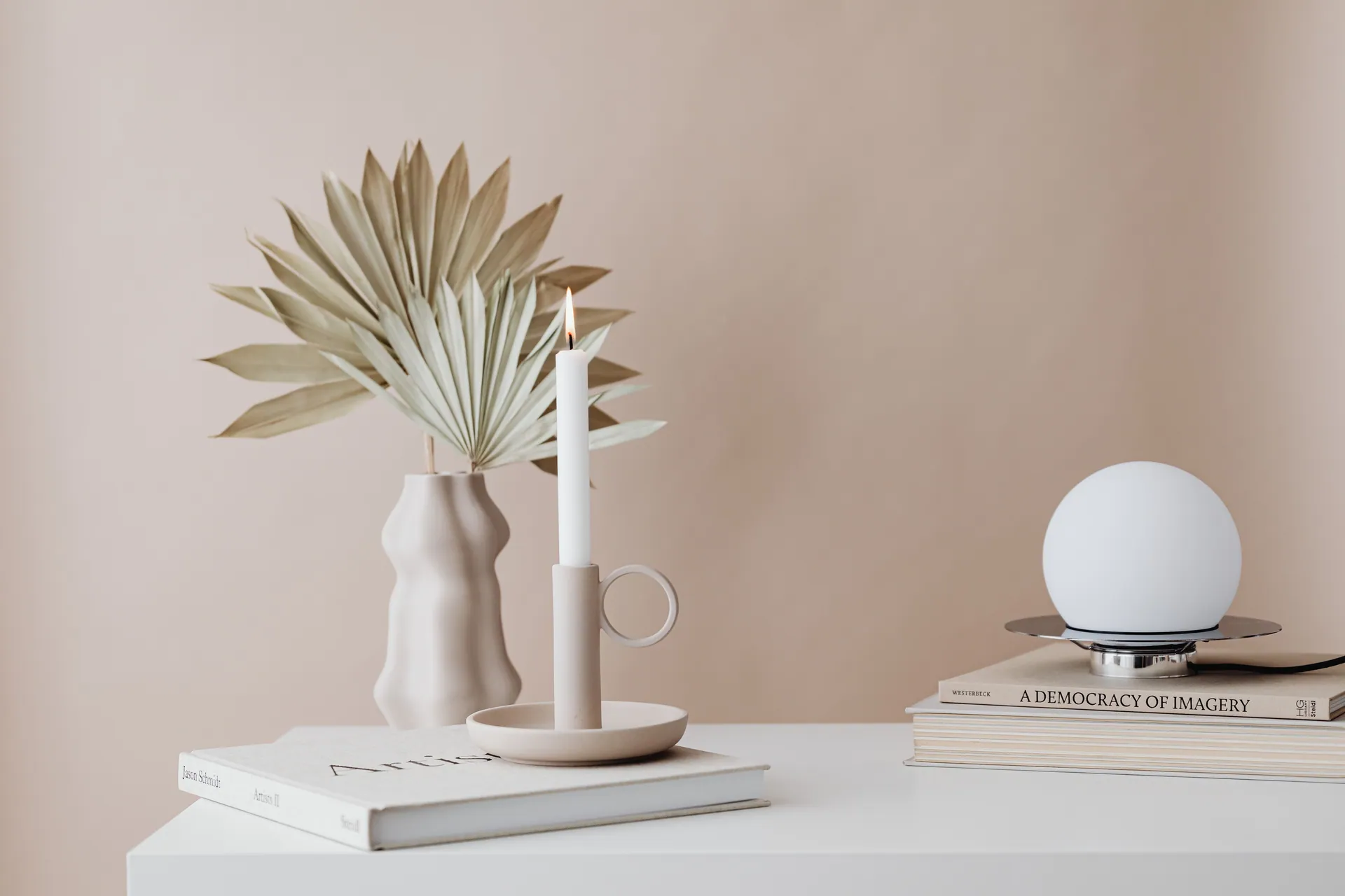 A minimalist setup featuring a candle, books, and modern home decor.