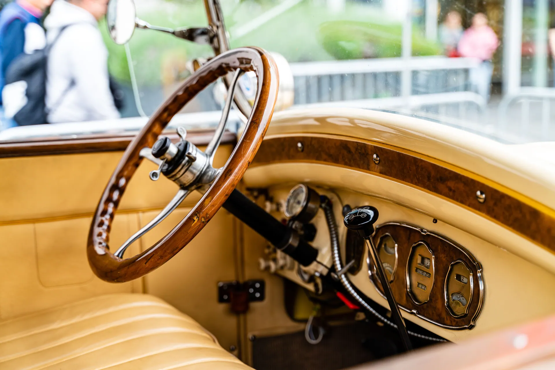Close-up of a classic car interior showcasing a wooden steering wheel and vintage details.