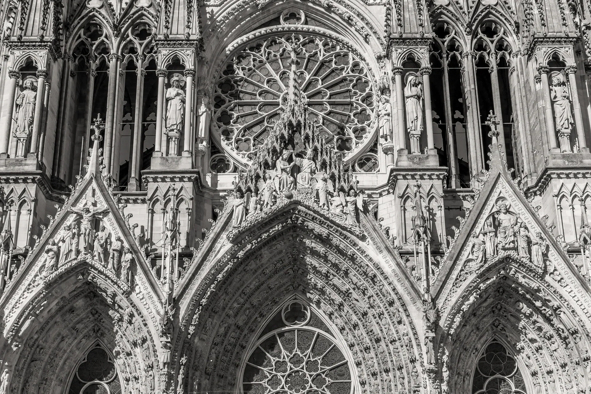 Intricate facade of Reims Cathedral captured in monochrome, highlighting gothic architecture's detailed craftsmanship.