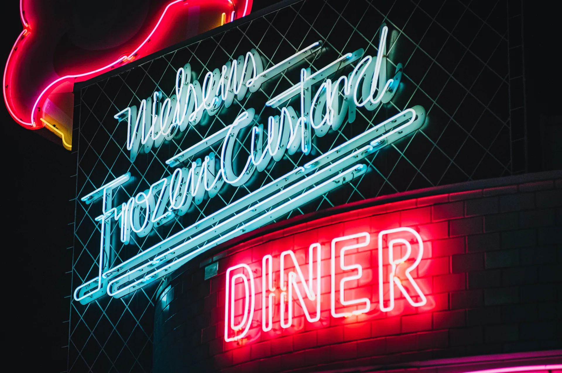 Colorful neon signs illuminate a retro diner at night, creating a nostalgic ambiance.