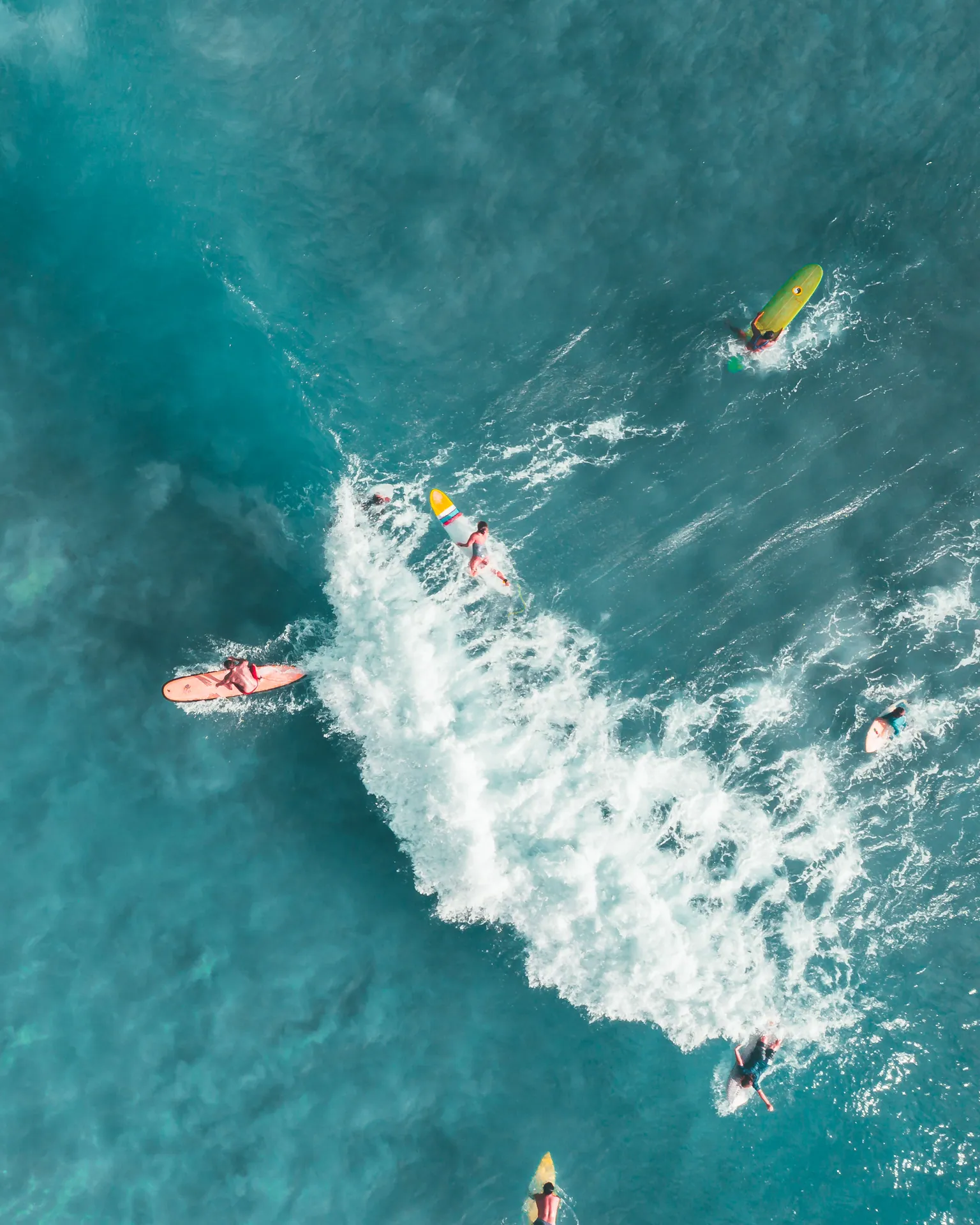 Dynamic aerial shot capturing surfers riding ocean waves, showcasing vibrant water sports action.