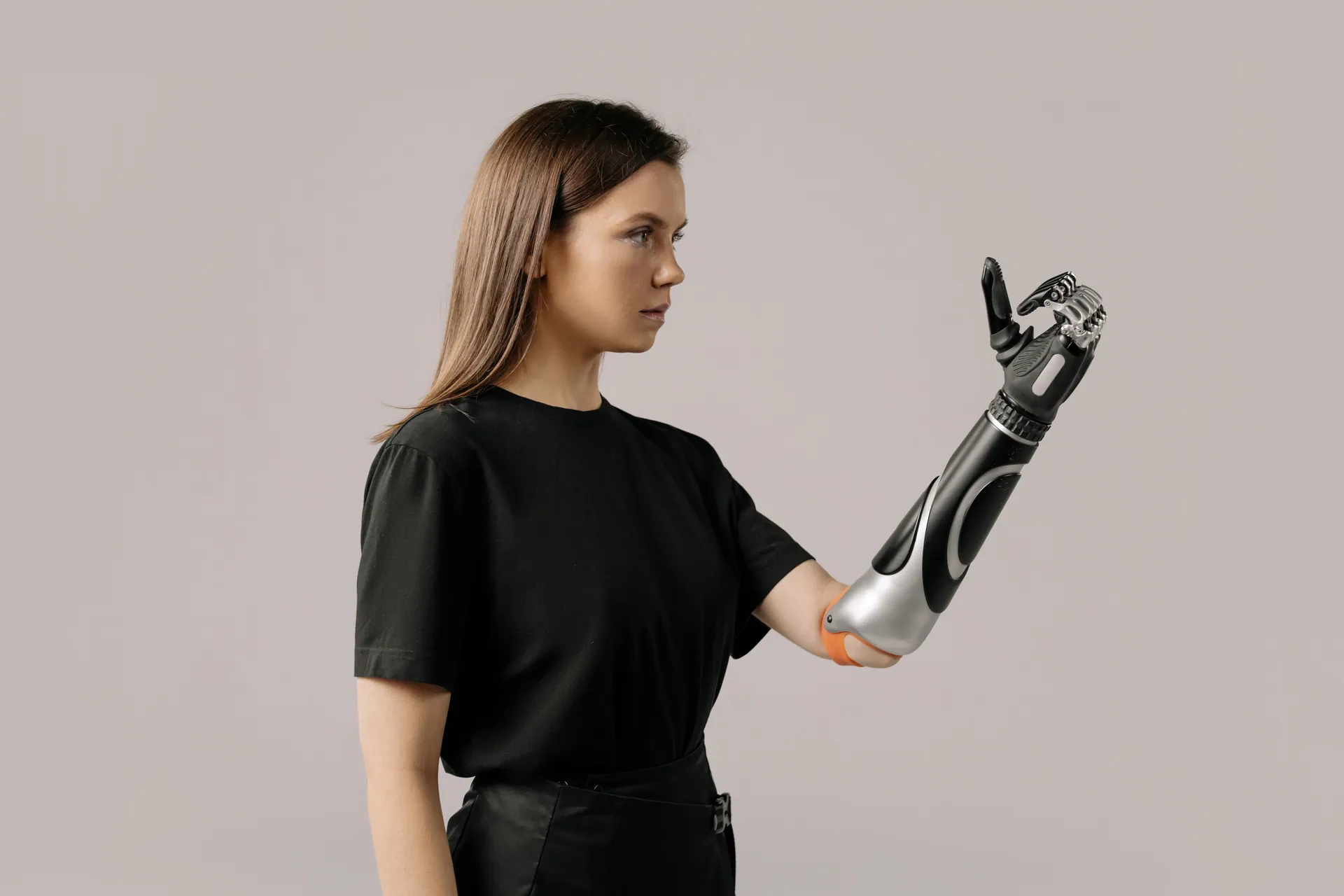 Portrait of a woman with a prosthetic arm wearing a black shirt. Studio lighting.