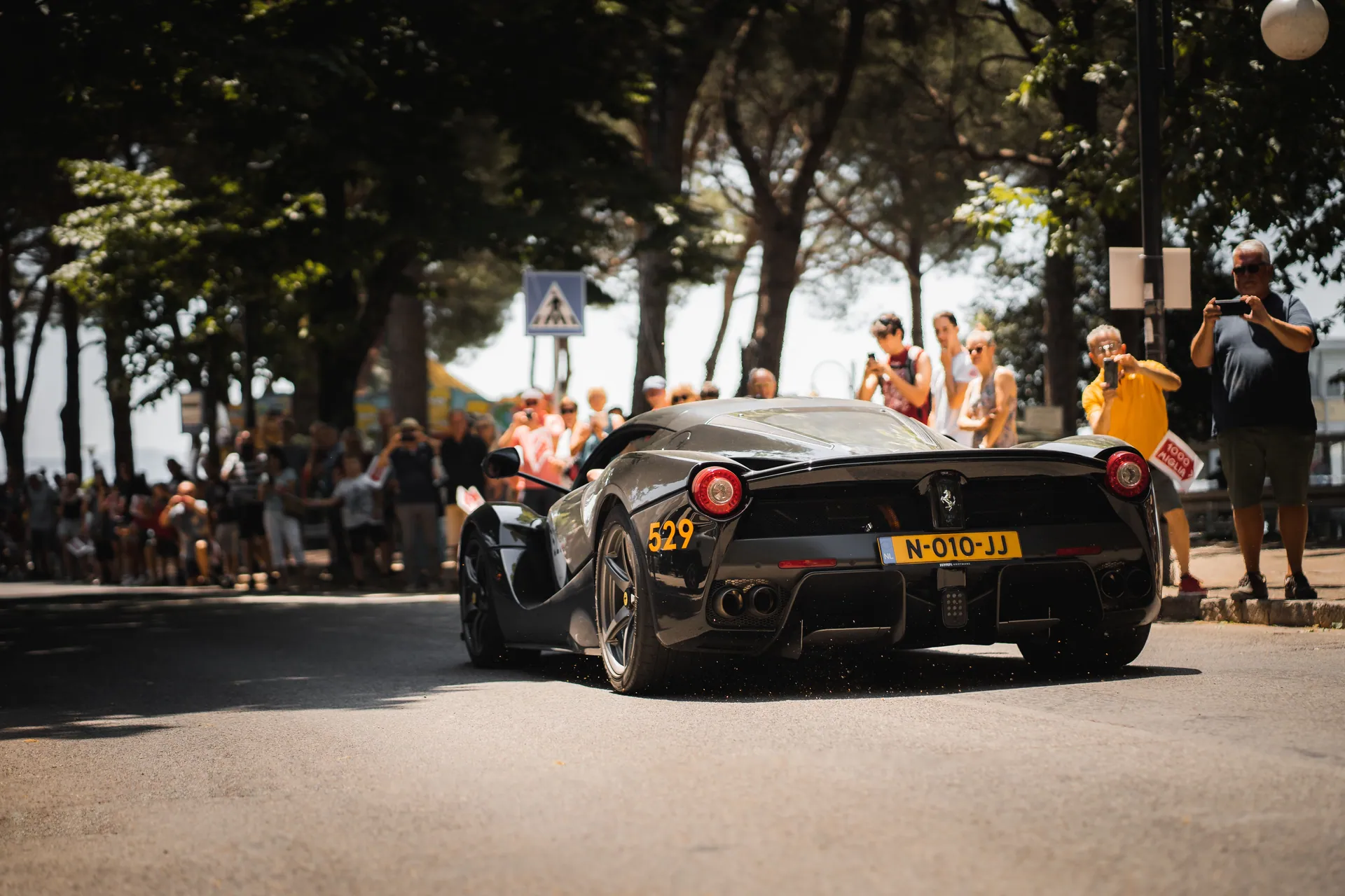 Elegant sports car showcased in a vibrant outdoor car event with spectators.