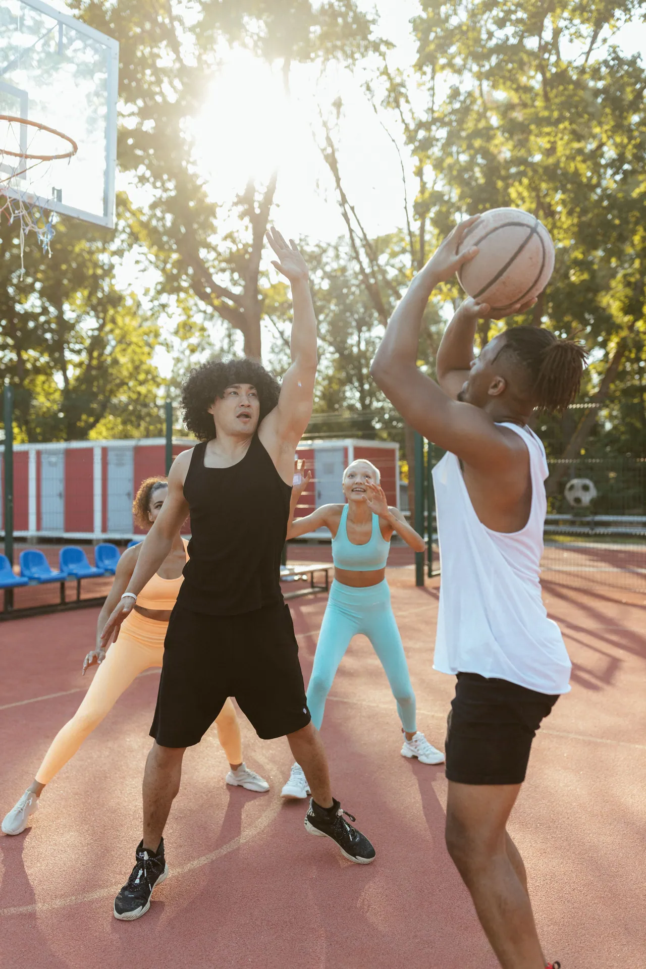 Diverse group engaging in a lively basketball game on an outdoor court.