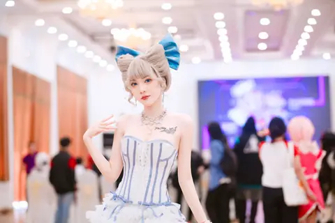 A young woman in detailed cosplay attire with a distinct blue bow at a convention.