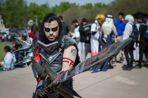 A man in detailed warrior cosplay at an outdoor festival, captivating portrait.