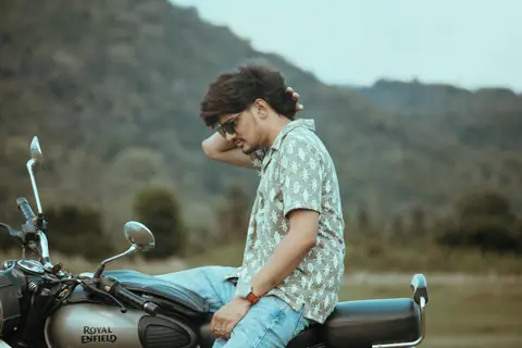 A man sits on a motorcycle in a picturesque outdoor setting, embodying leisure and adventure.