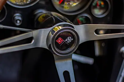Detailed image of a Chevrolet Corvette steering wheel showcasing the iconic logo and metallic design.