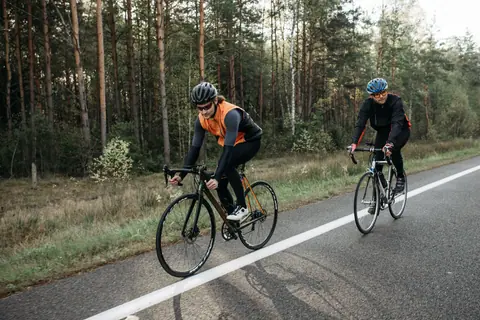 Two cyclists enjoying a ride through a scenic forest road, showcasing active lifestyle and outdoor recreation.