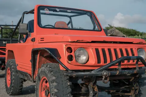 Close-up of a rugged off-road jeep parked on a sandy landscape under a clear sky.
