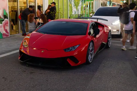 A sleek red Lamborghini Huracan displayed at a bustling outdoor car meet.