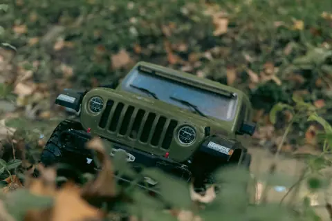 A realistic miniature green toy Jeep blends into a lush forest environment.