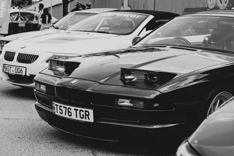 A lineup of vintage sports cars showcased in a parking lot, captured in black and white.