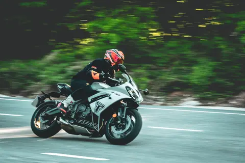 Motorcyclist in full gear racing on a winding road, showcasing speed and agility.
