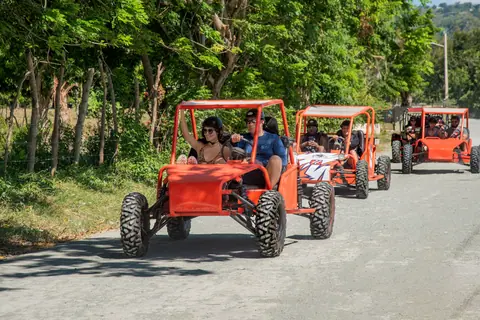 Group enjoying a thrilling buggy ride on a scenic forest road under clear skies.
