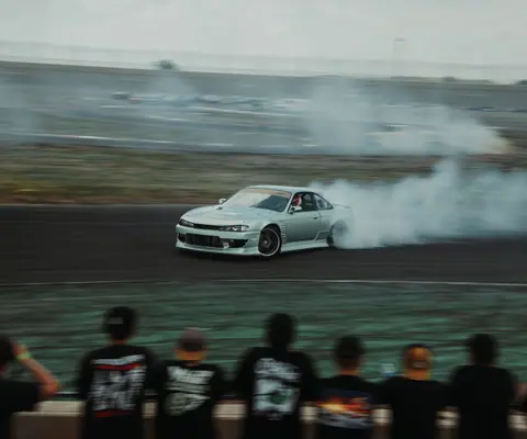 Nissan sports car drifts on a racetrack in Colorado, captivating spectators with smoky action.