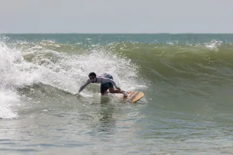 Surfer expertly rides a wave on a sunny day, capturing the thrill of ocean water sports.
