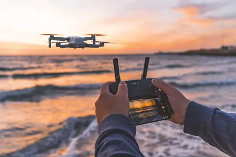 A drone is controlled over the ocean in Fremantle during a beautiful sunset, showcasing modern technology.