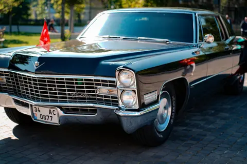 Vintage black Cadillac on cobblestone street, sunlight reflecting off the polished surface.
