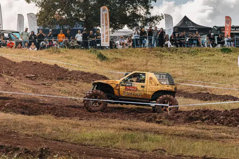 Exciting offroad race featuring a rugged 4x4 vehicle and enthusiastic spectators in a natural setting.
